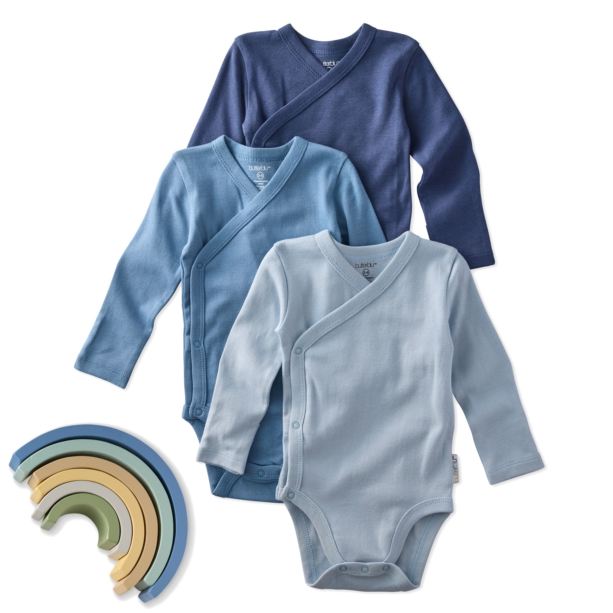 Three baby garments including a blue wrap, a navy long-sleeve shirt, and a light blue onesie, with a rainbow-shaped toy on a white background.