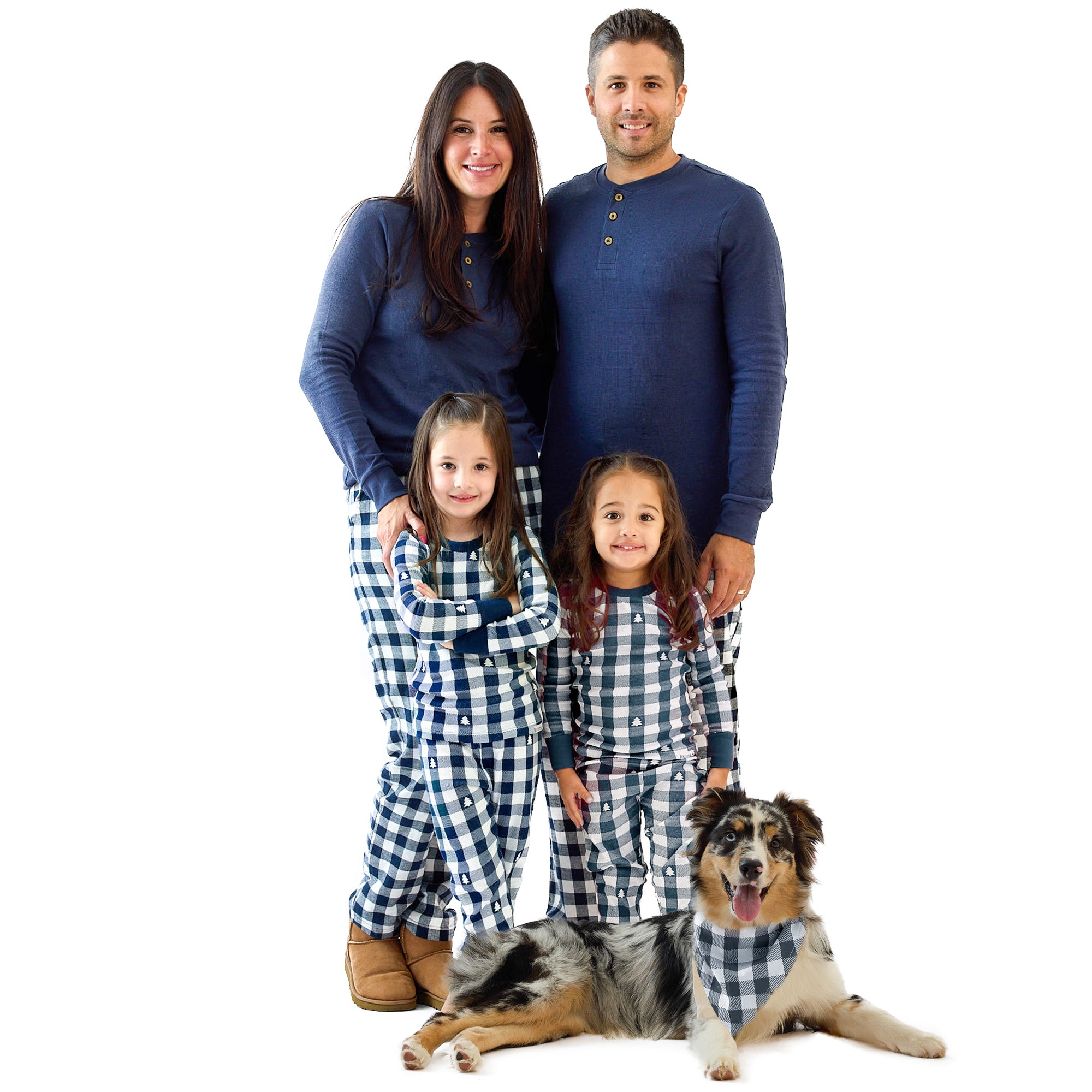 Family of four in matching blue and white checkered pajamas with a dog on a white background