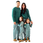 Family of four wearing matching green and white checkered pajamas on a white background