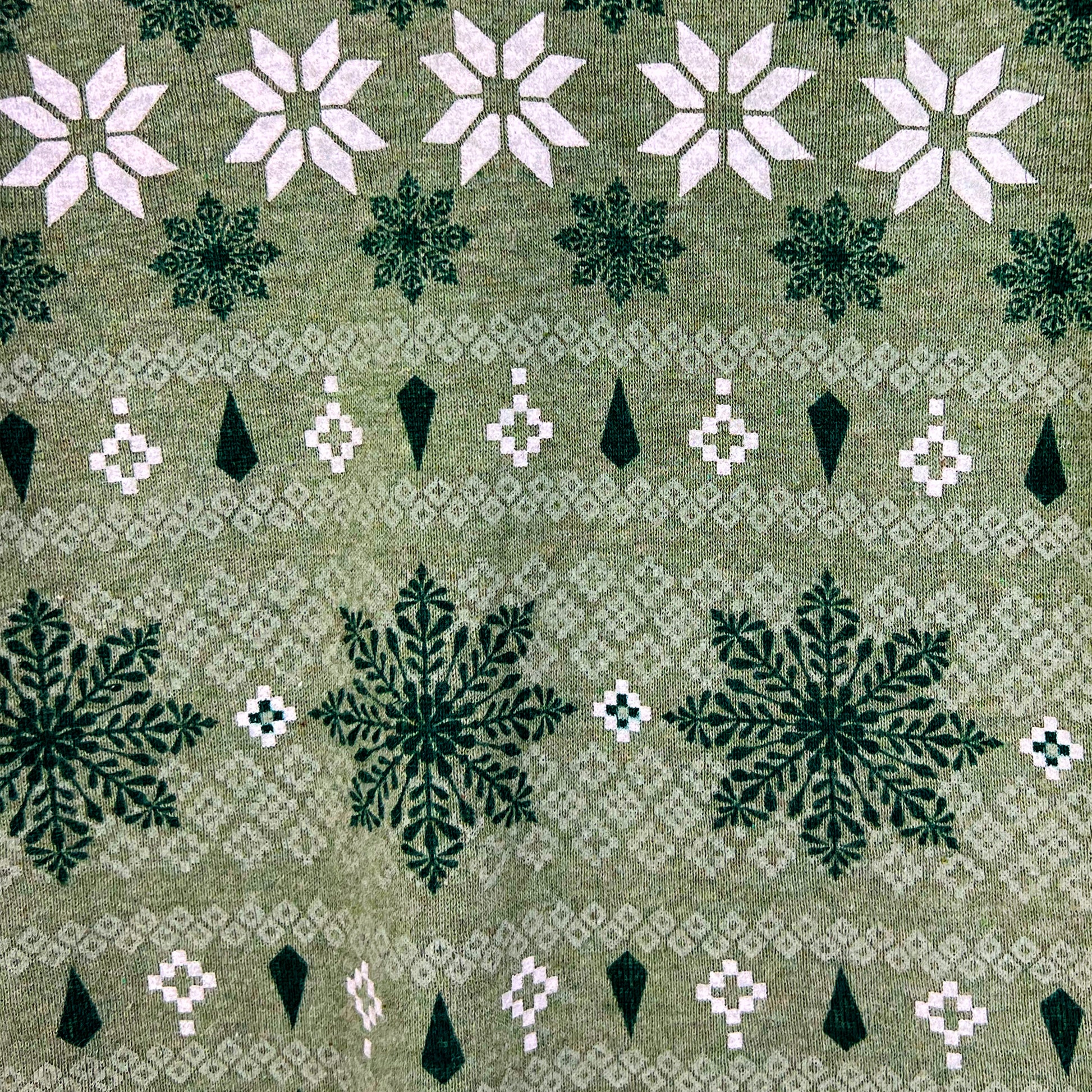 Patterned fabric with snowflakes and geometric shapes on a green background
