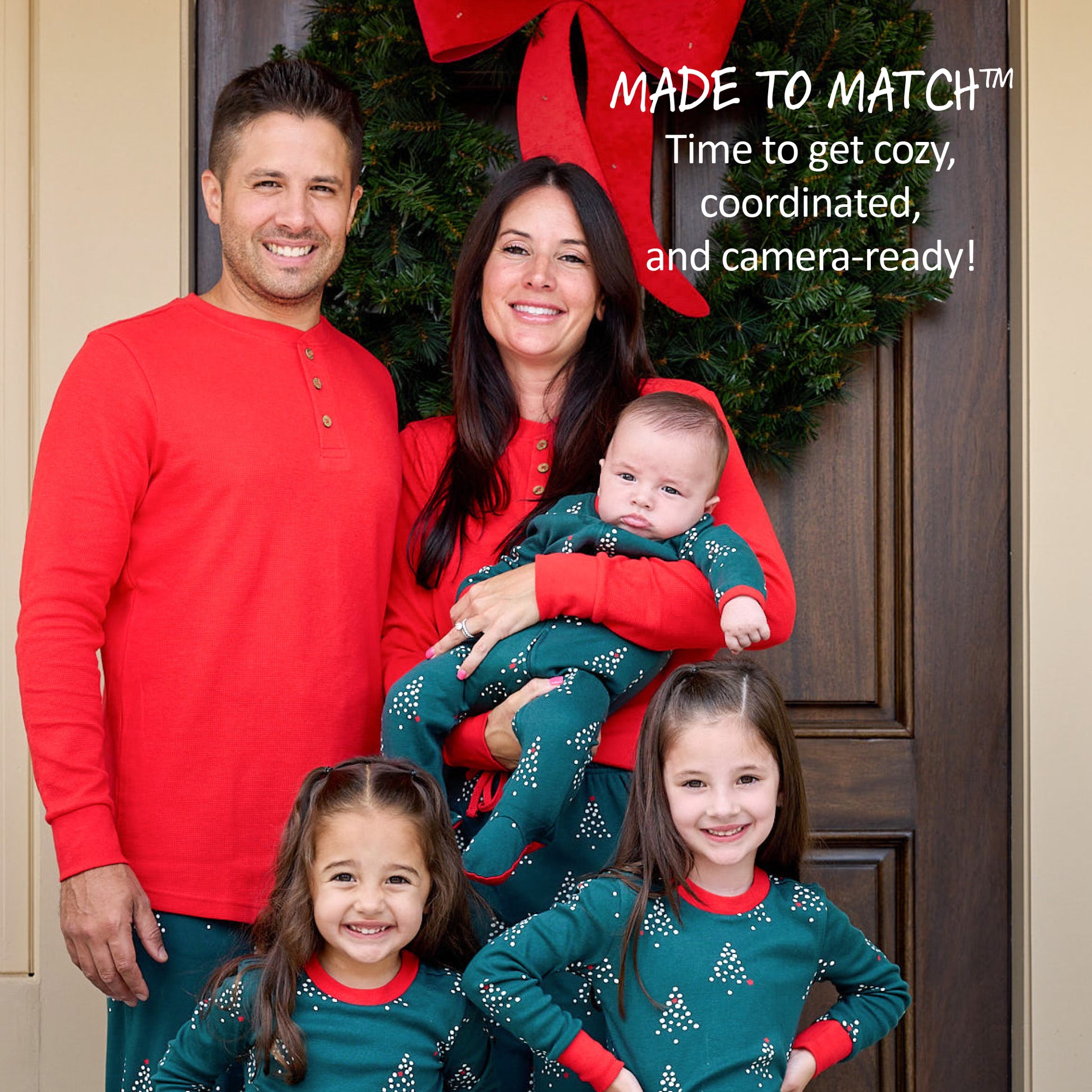 Family of five wearing matching red and green pajamas in front of a decorated door.