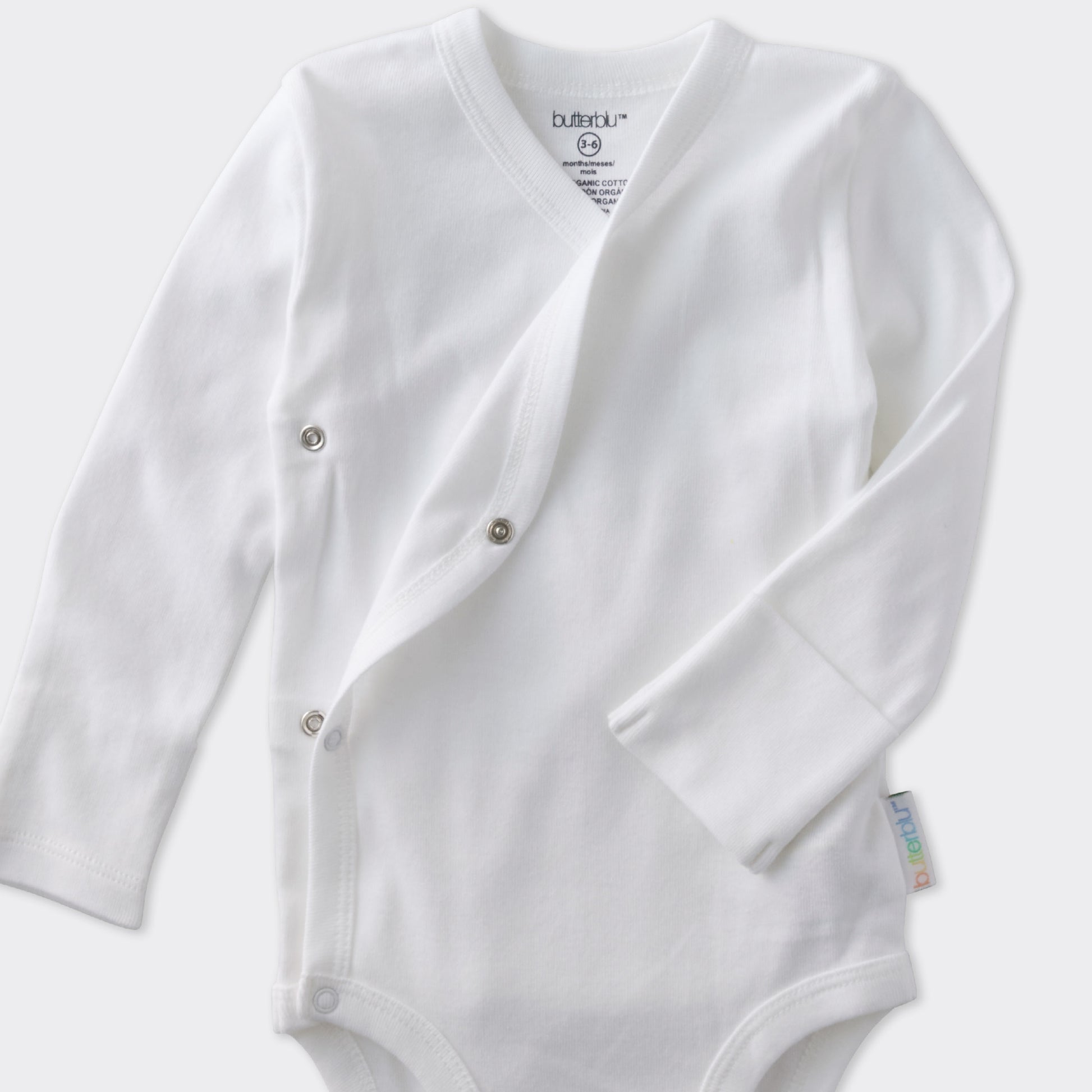 White baby onesie with buttons on a light gray background