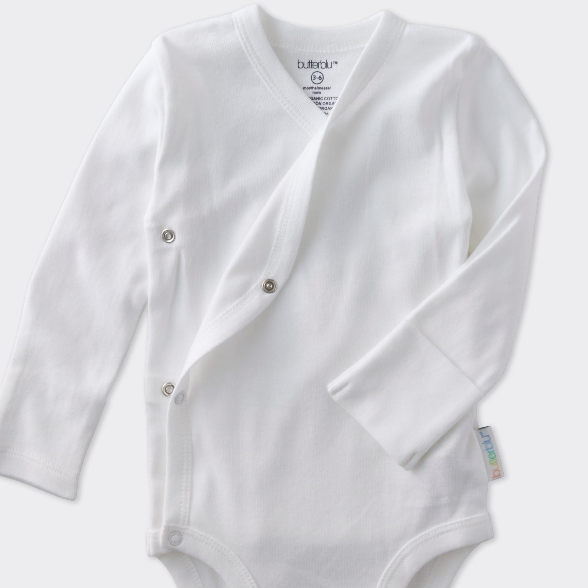White baby onesie with buttons on a light gray background