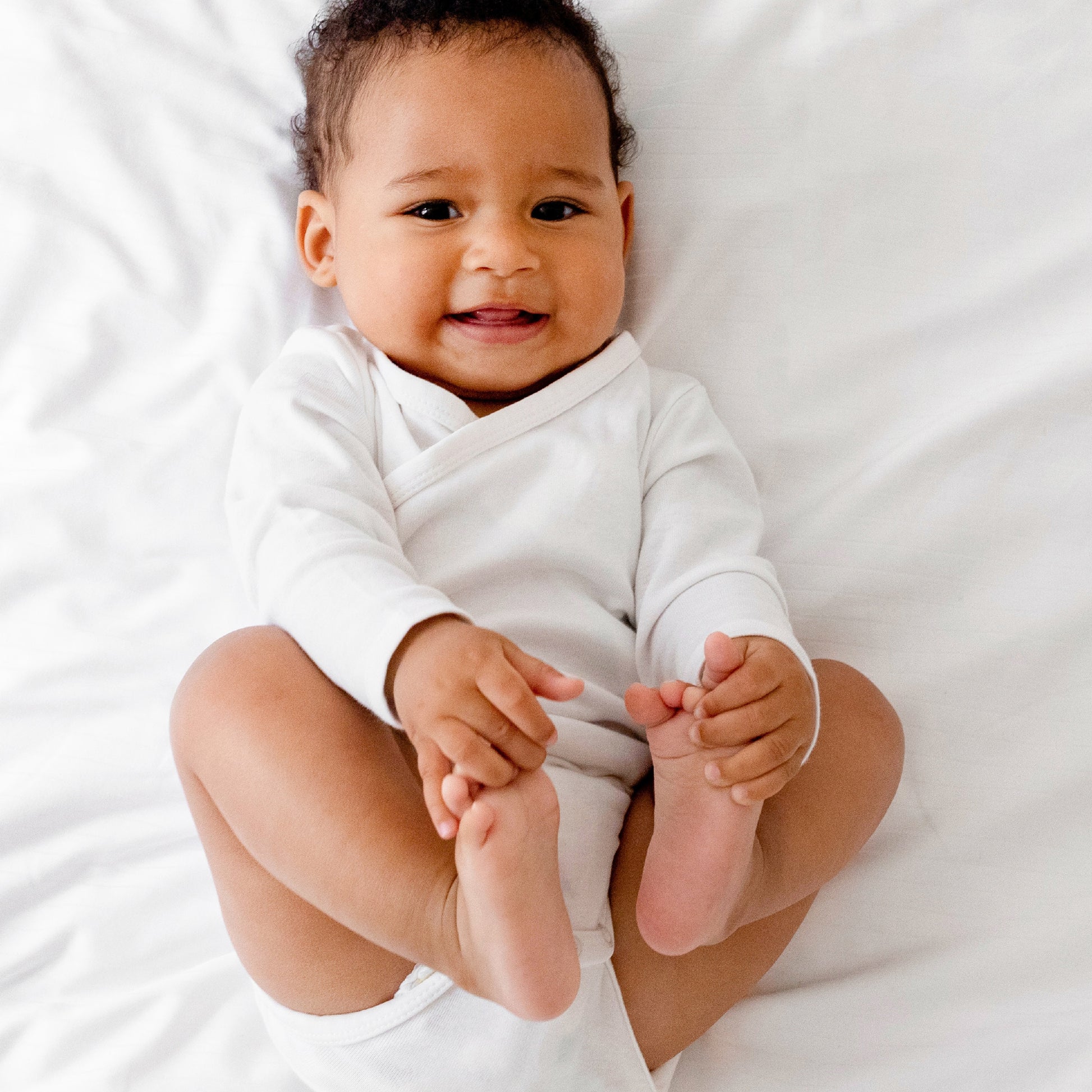 Baby in a white onesie lying on a white surface