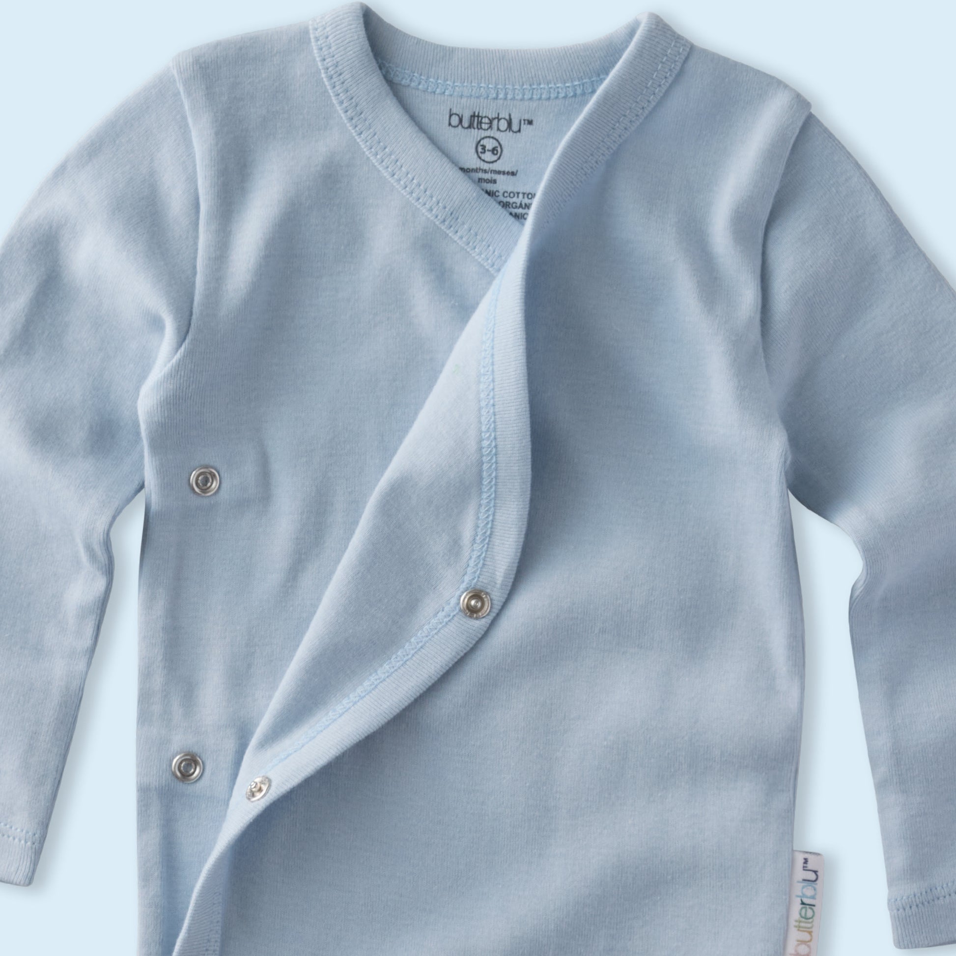 Light blue baby cardigan with buttons on a light blue background
