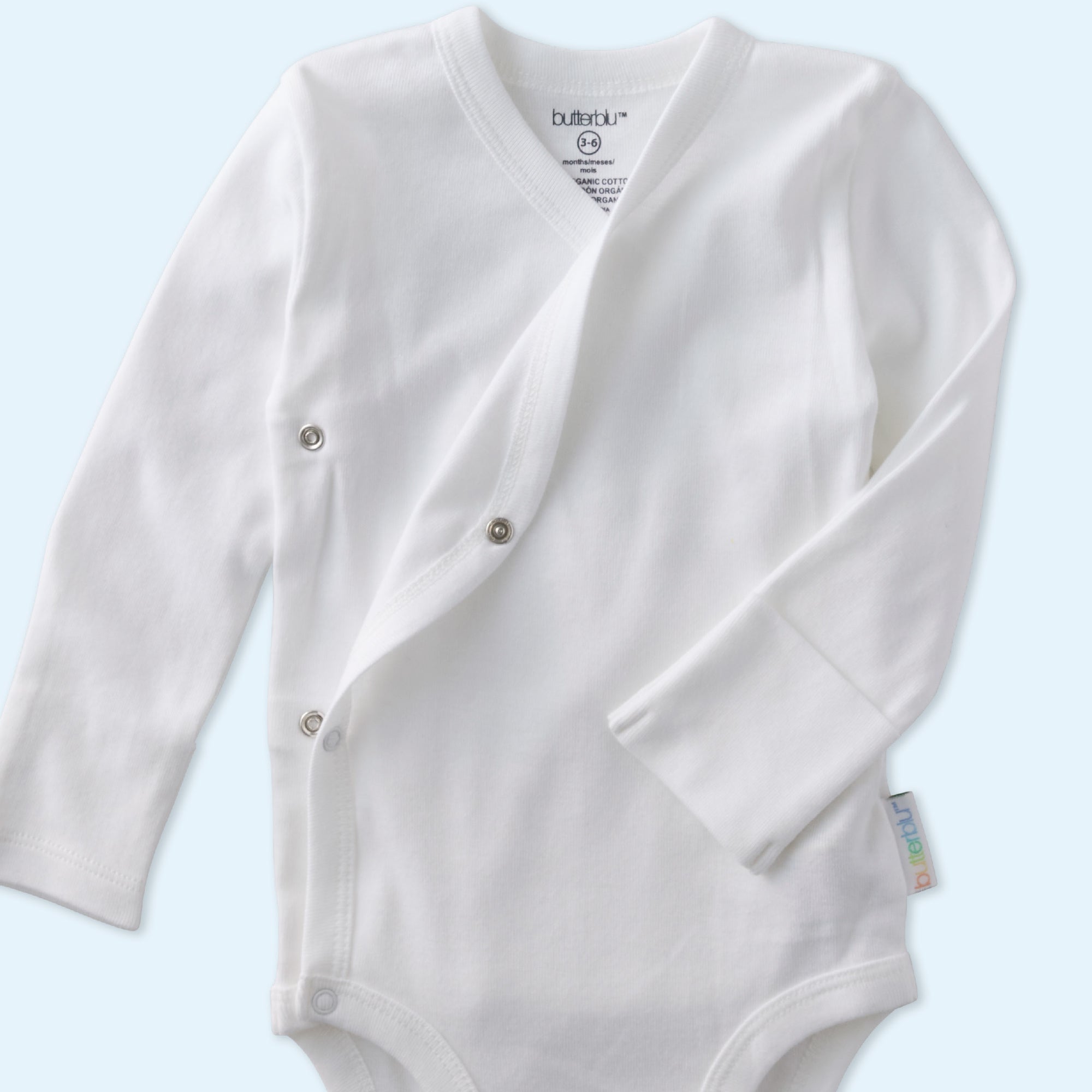 White baby onesie with buttons on a light blue background