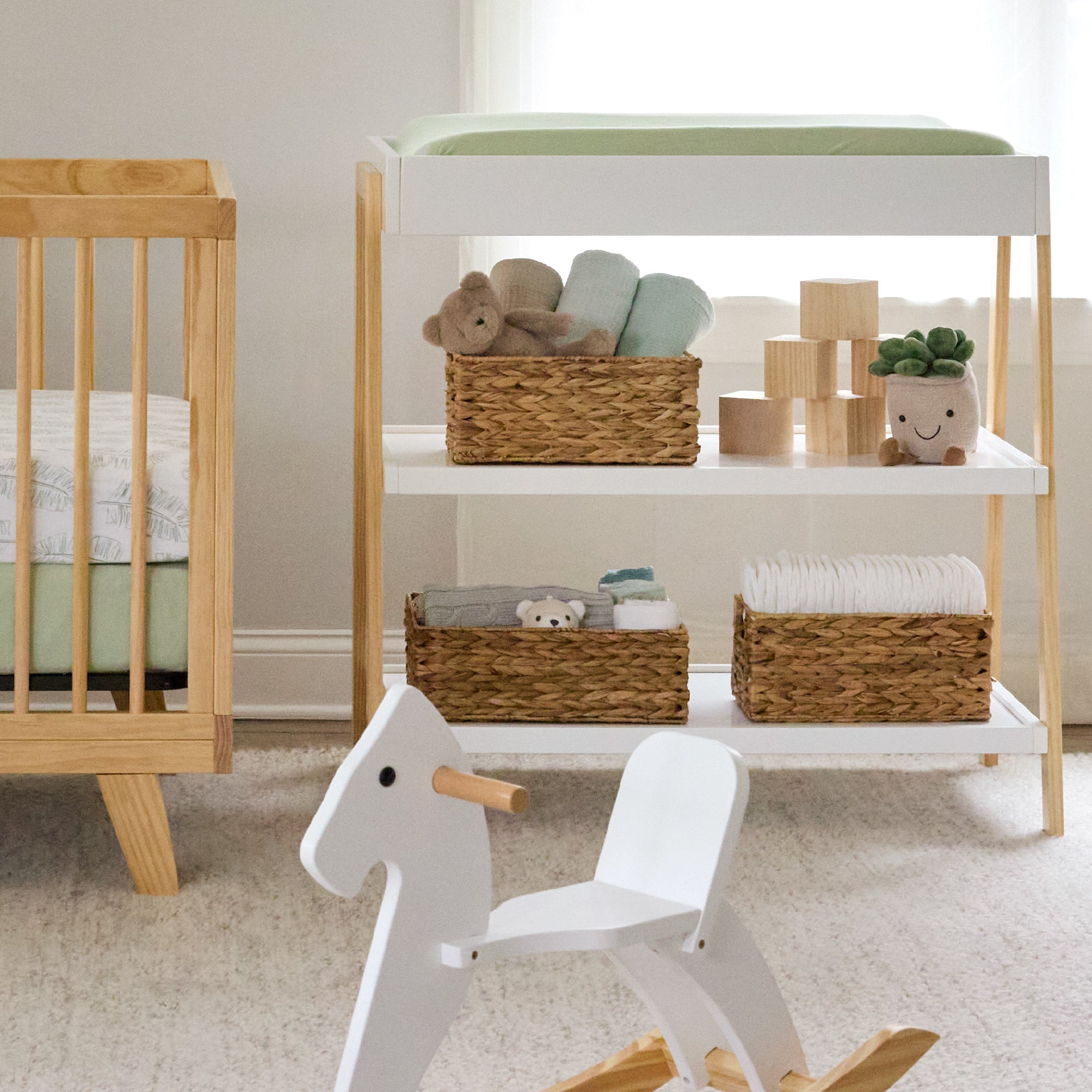 Nursery room with wooden crib, changing table, and toys on a light-colored floor.