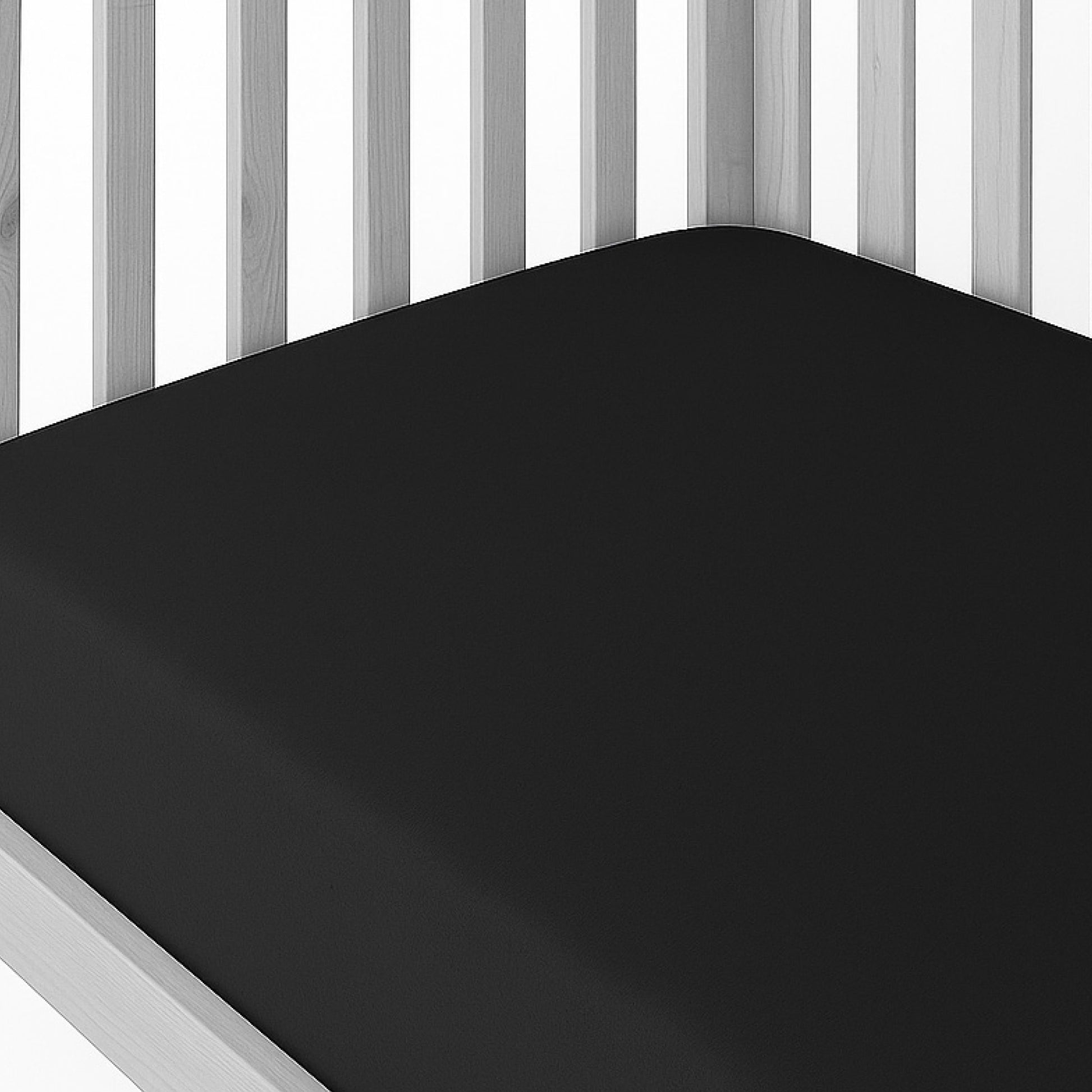 Black mattress cover on a bed with white wooden headboard and footboard.