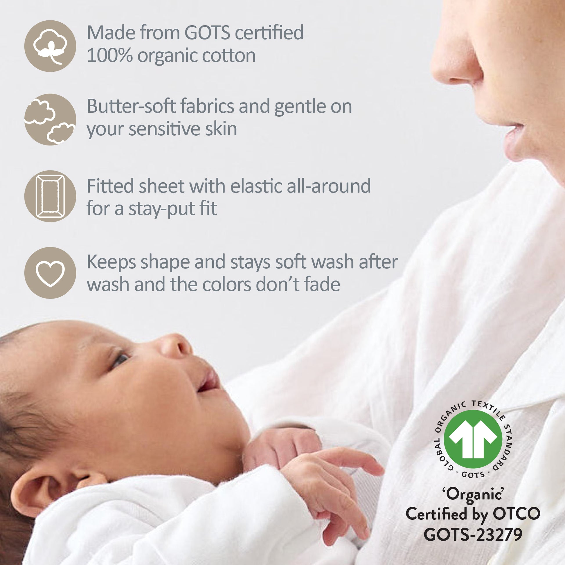 Baby wrapped in a fitted sheet with GOTS certification label, close-up of baby and mother.