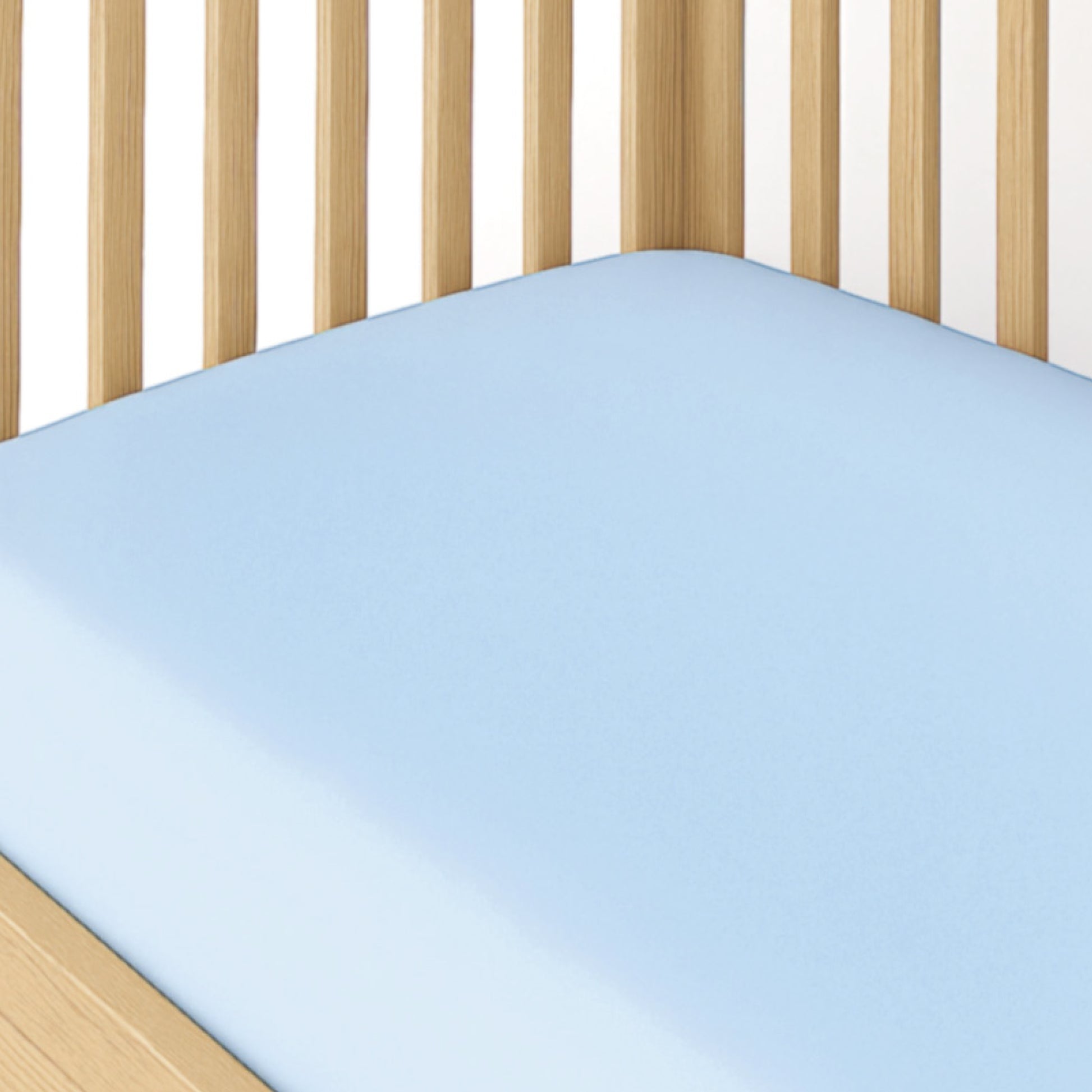 Crib with a blue fitted sheet and wooden sides on a white background