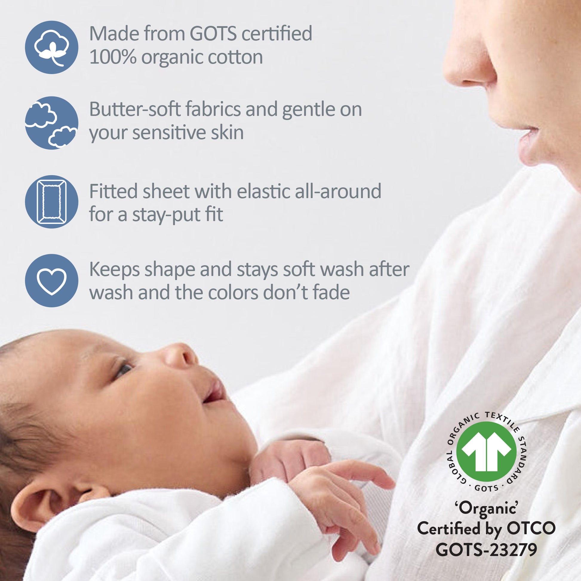 Baby wrapped in a fitted sheet with GOTS certification label, close-up of baby and mother.