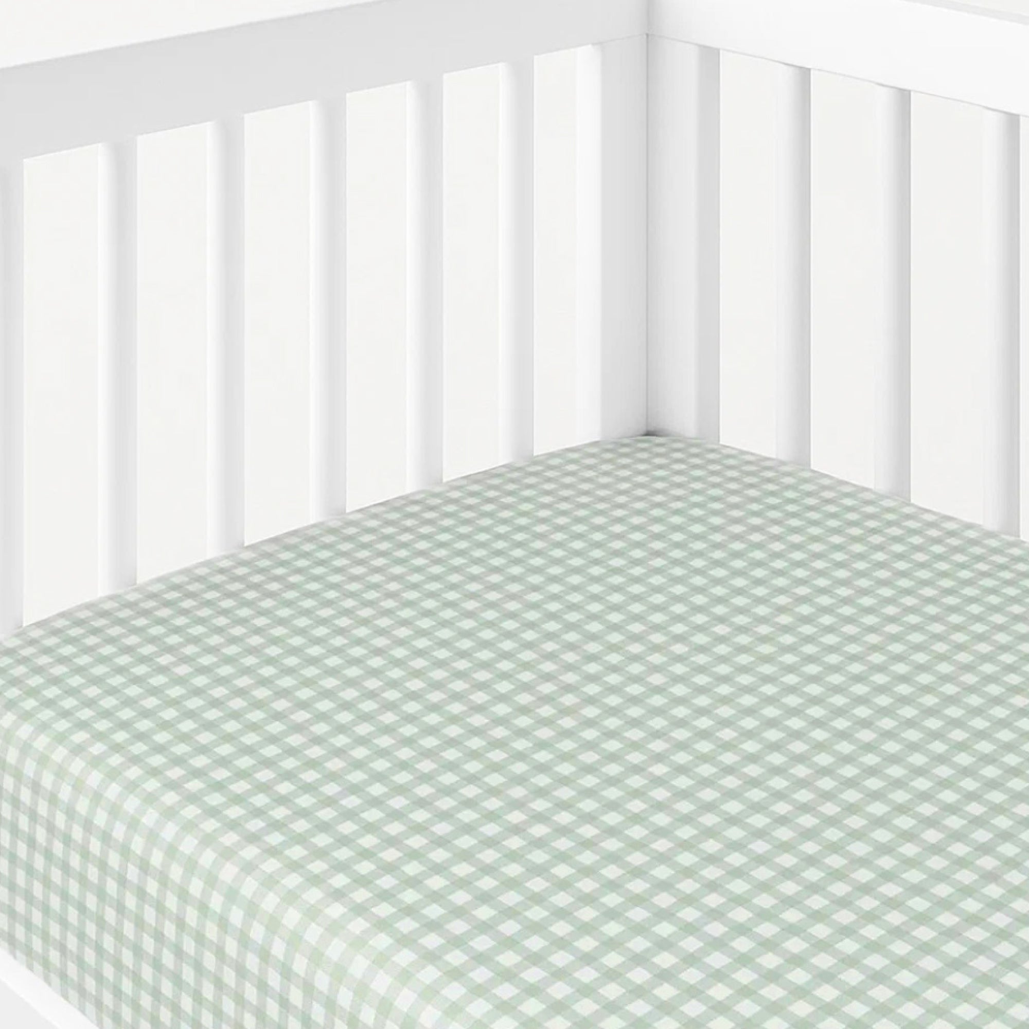 Crib with a green and white checkered fitted sheet on a white background