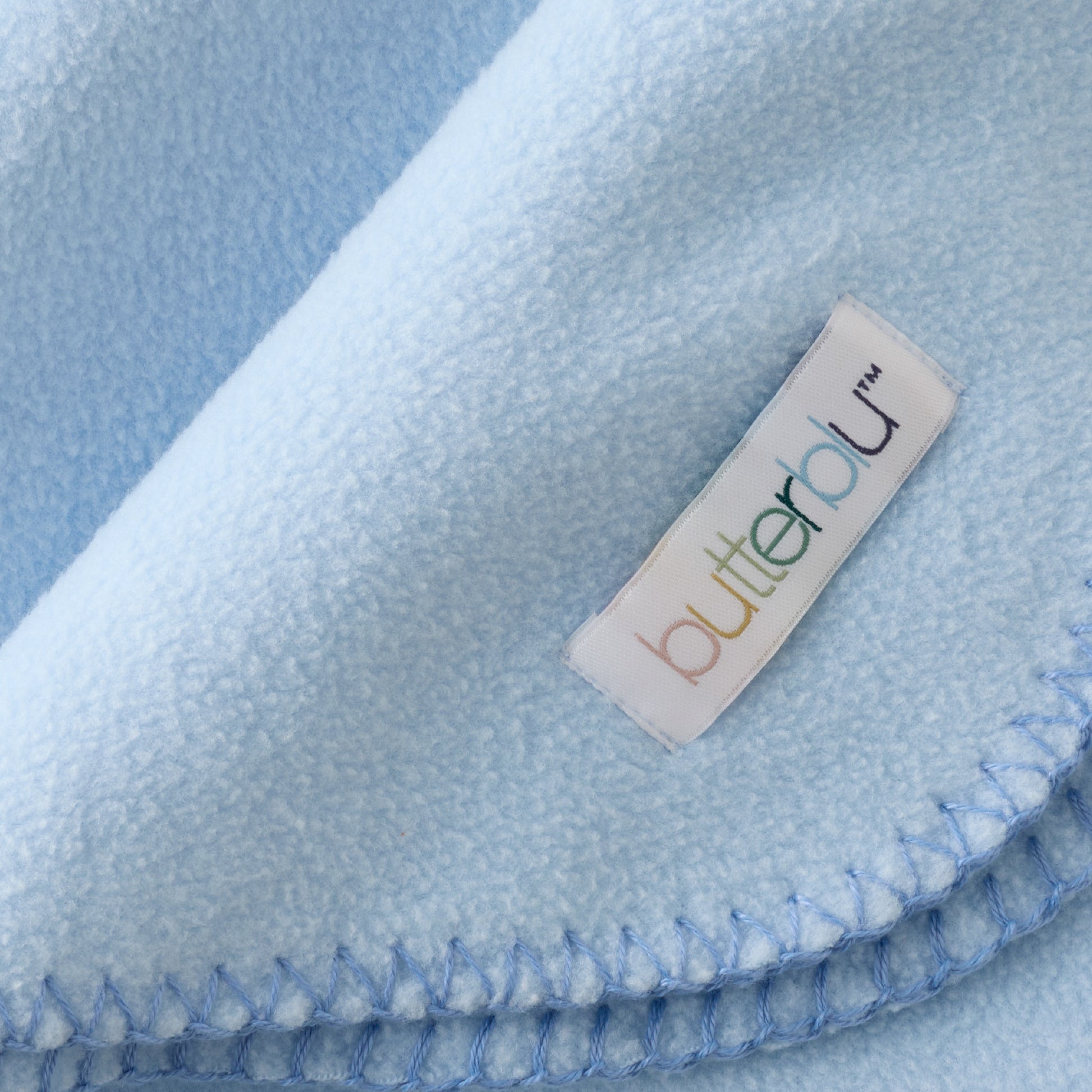 Close-up of a blue blanket with a 'butteralu' label.