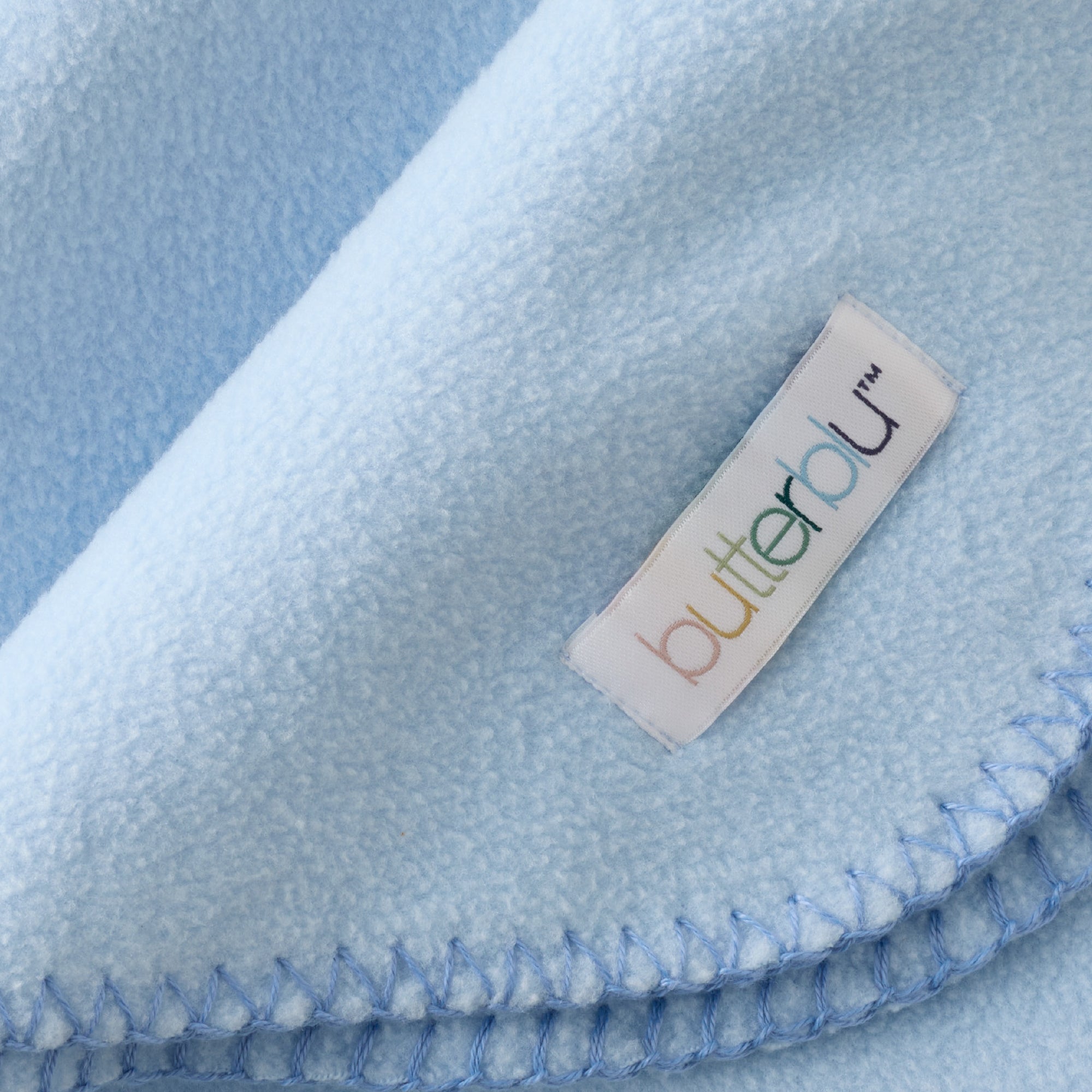 Close-up of a blue blanket with a 'butteralu' label.