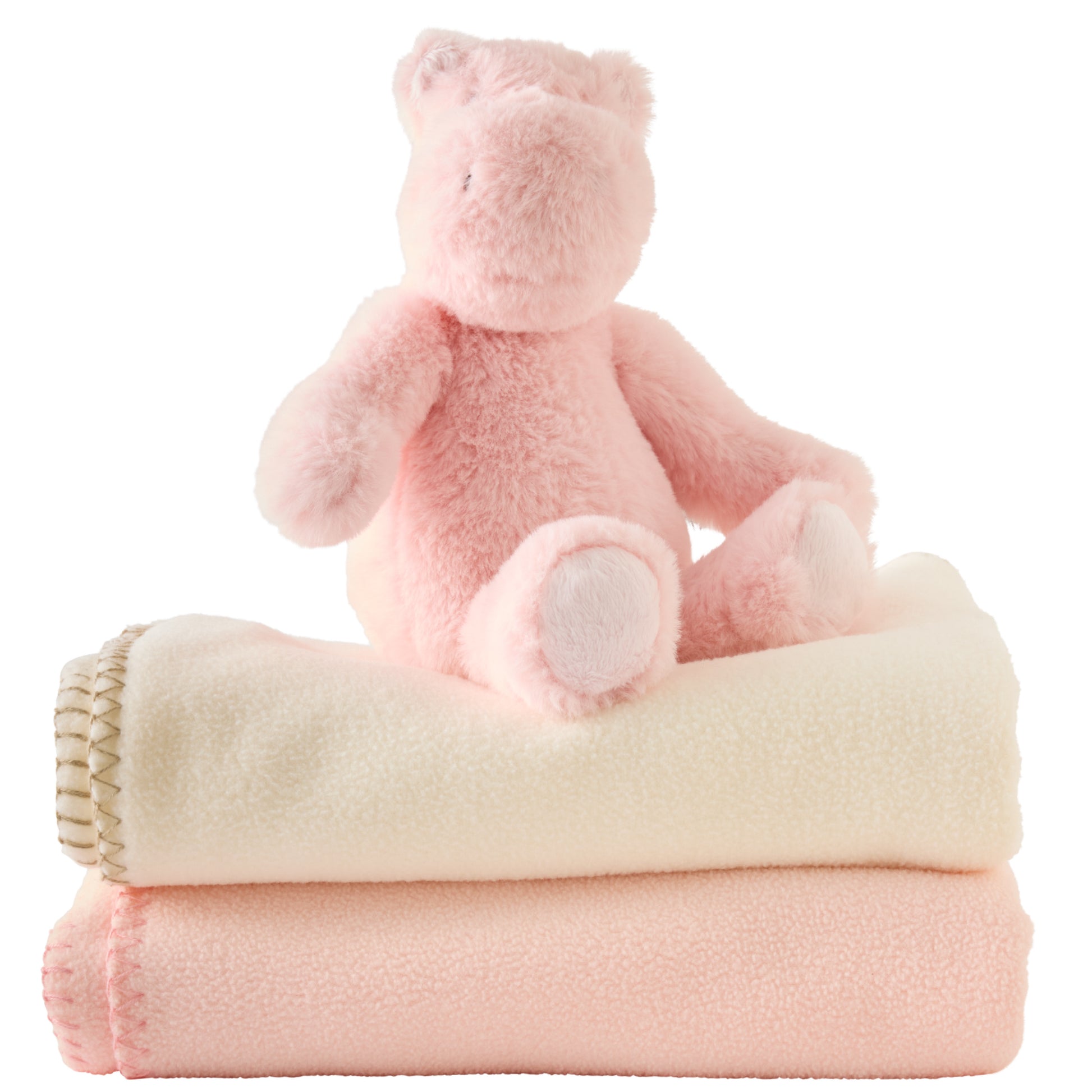 Pink teddy bear sitting on top of two folded blankets with a white background
