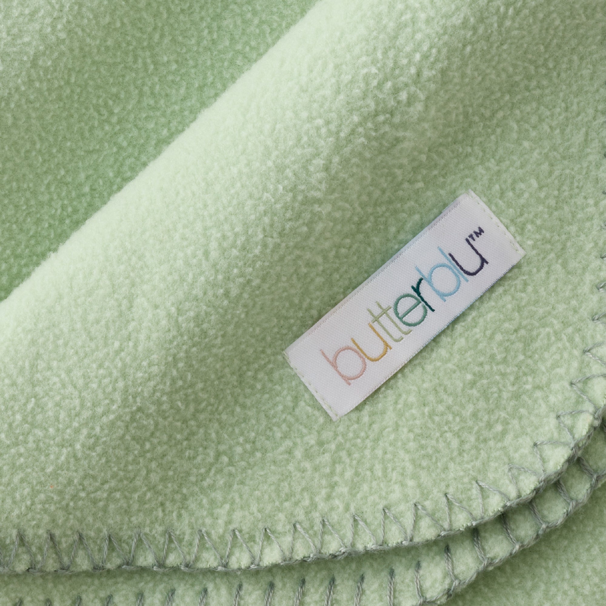 Close-up of a green fabric with a 'butterfly' brand label.