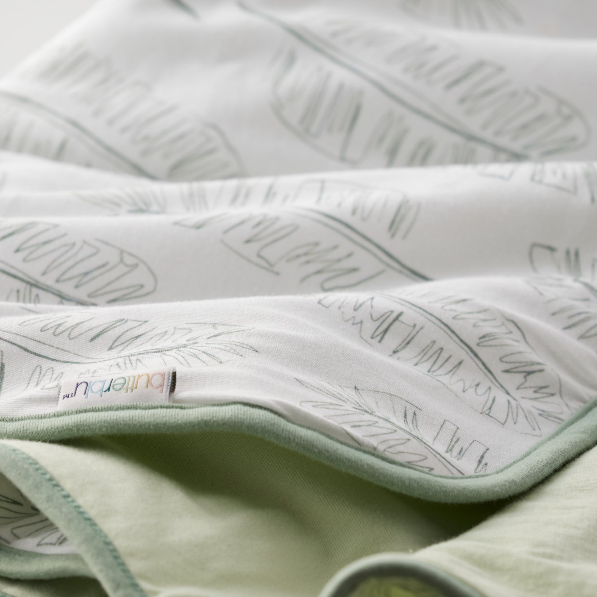 Close-up of a textured fabric with a brand label on a light green background