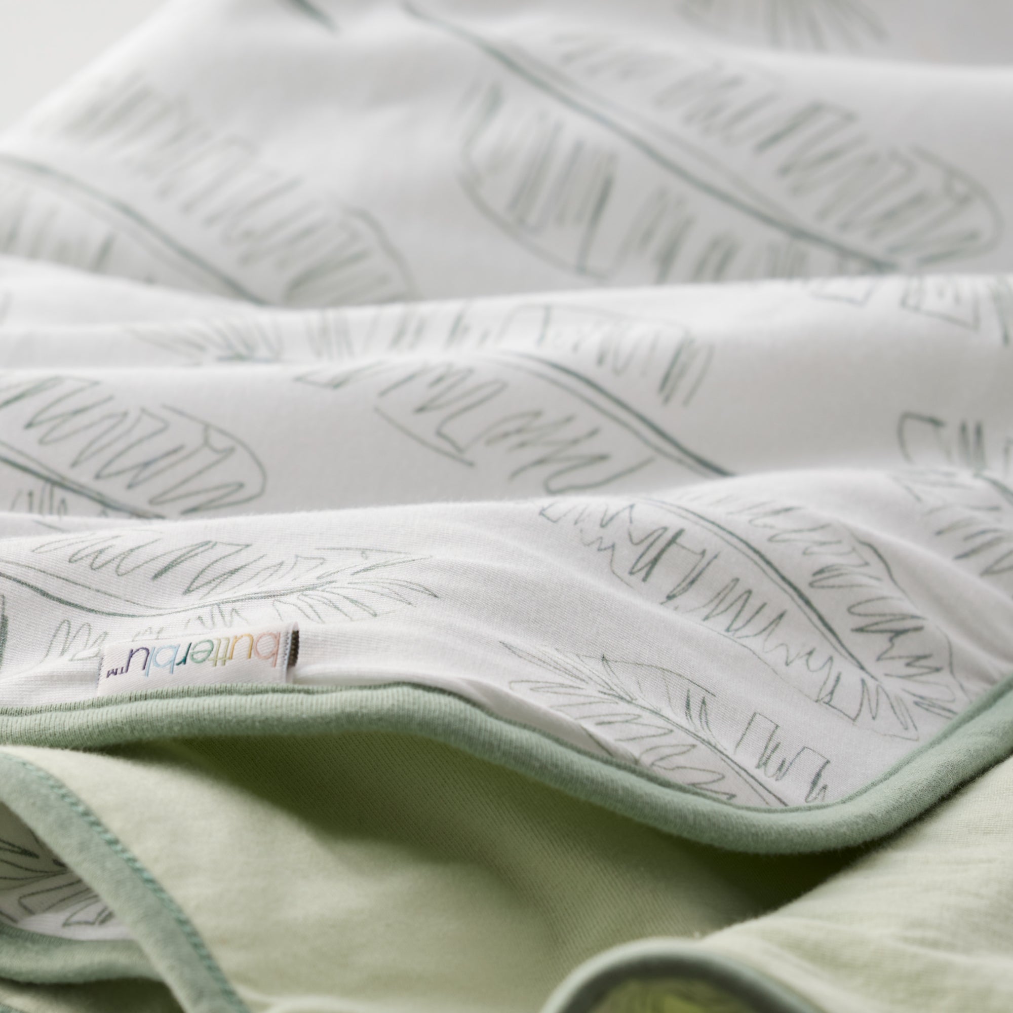 Close-up of a textured fabric with a brand label on a light green background