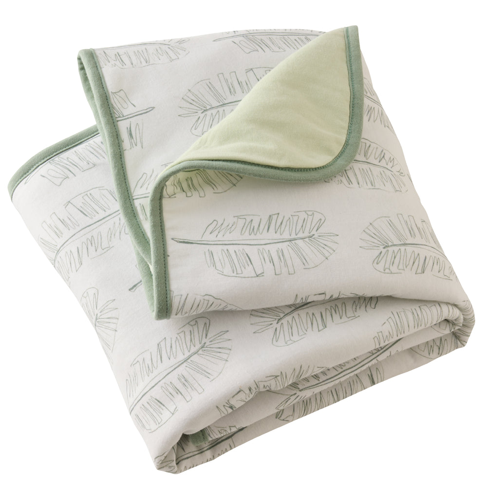 Folded blanket with leaf pattern and green border on a white background