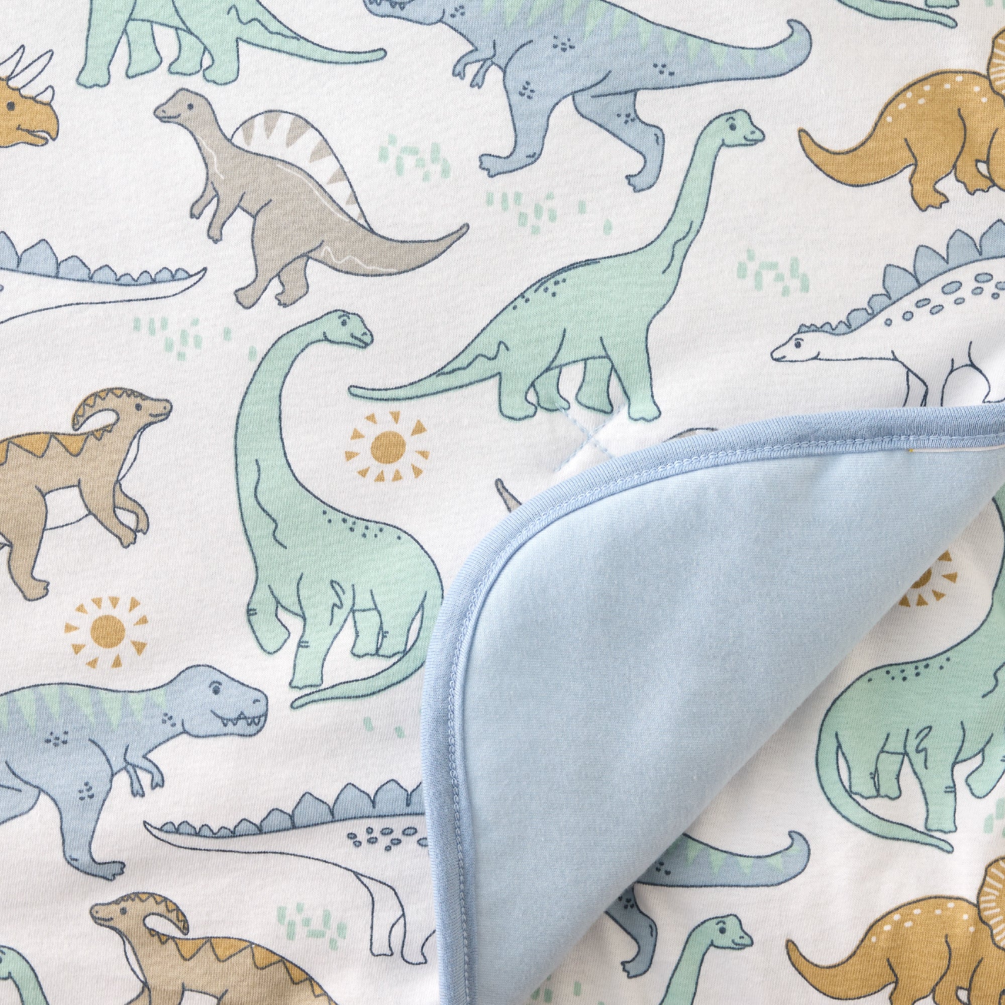 Fabric with dinosaur pattern and a folded blue fabric sample on top