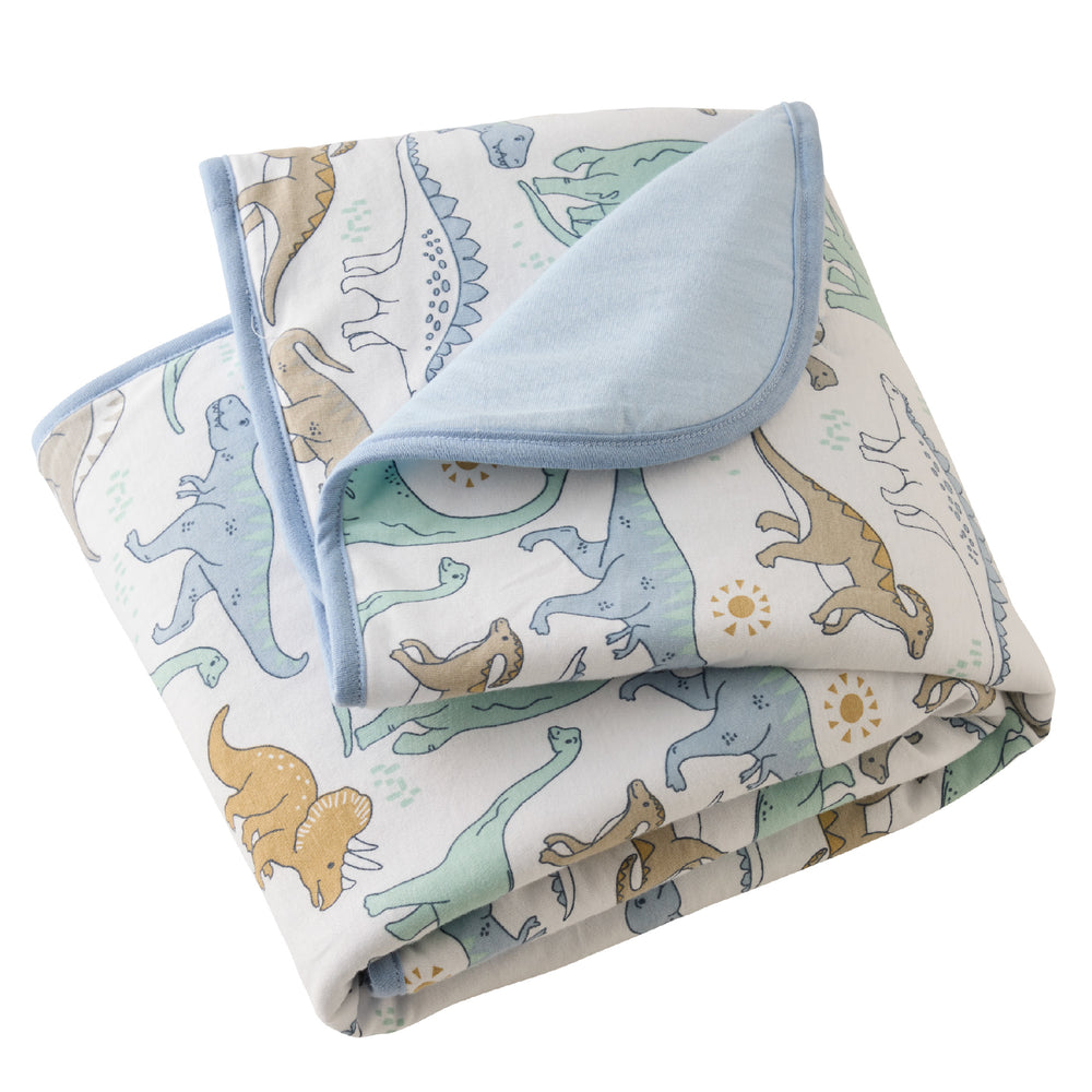 Folded baby blanket with dinosaur pattern on a white background