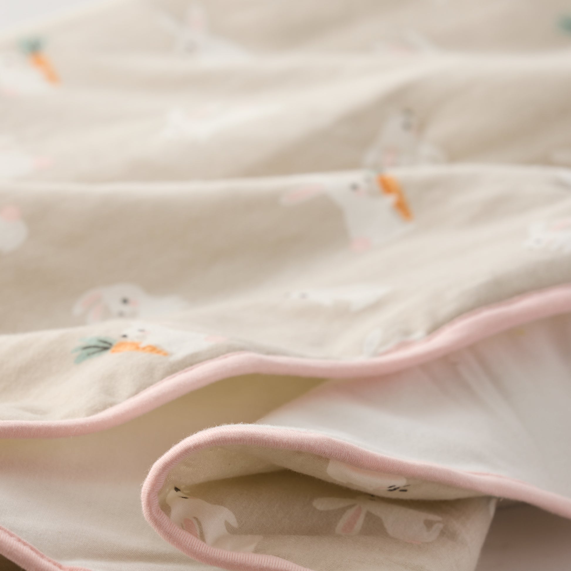 Close-up of a soft fabric with pink trim and small animal prints on a light background