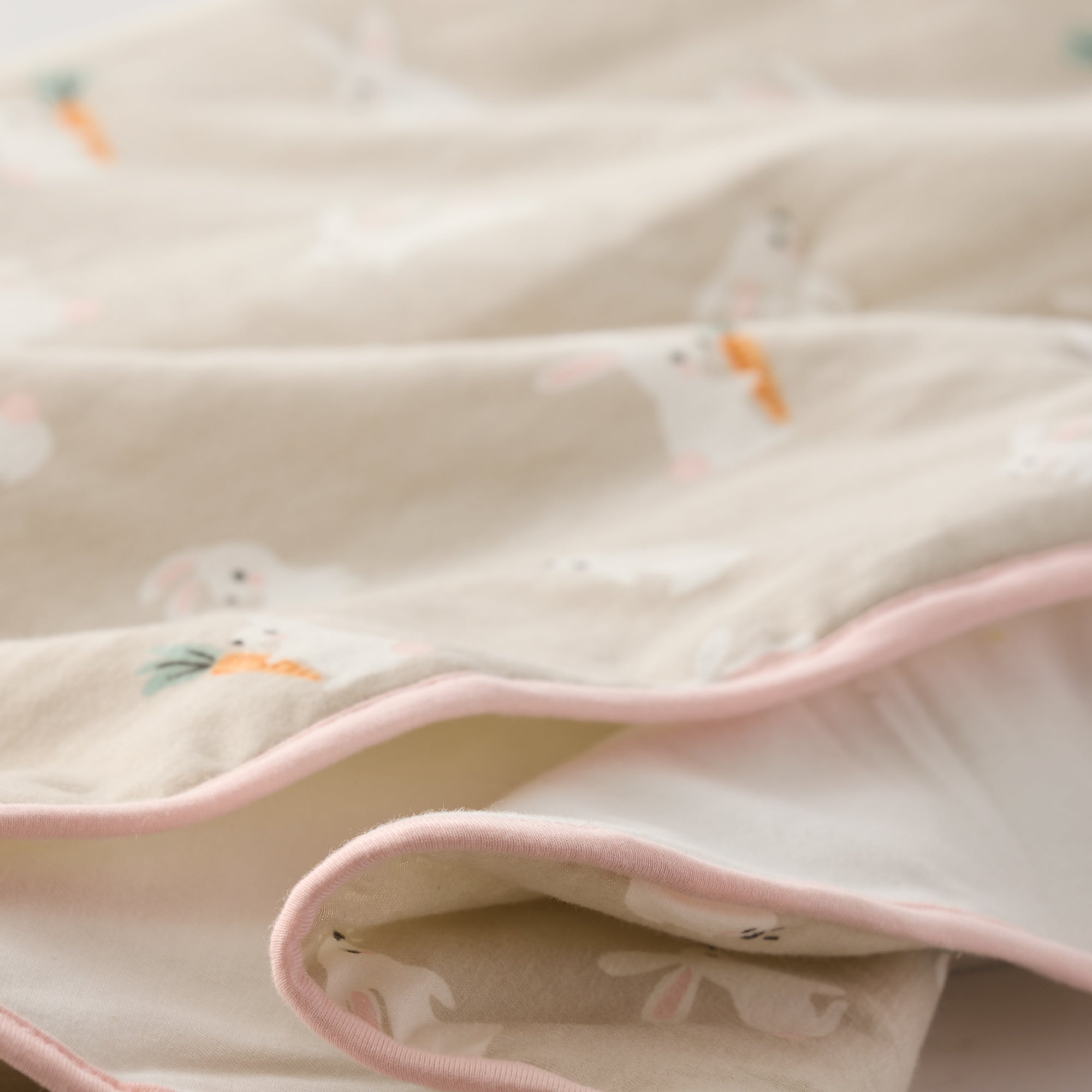 Close-up of a soft fabric with pink trim and small animal prints on a light background