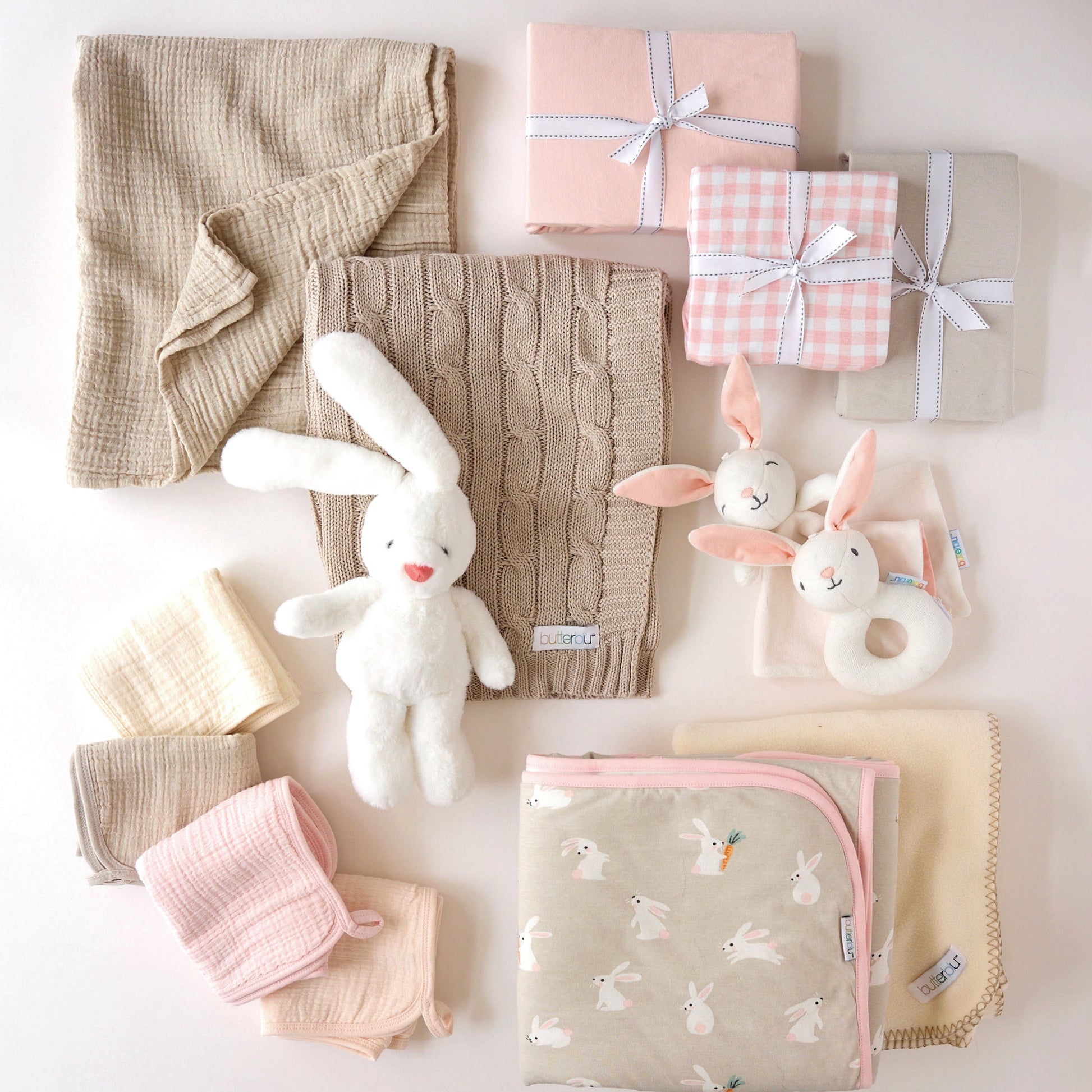 Collection of baby items including blankets, toys, and gift boxes on a light background