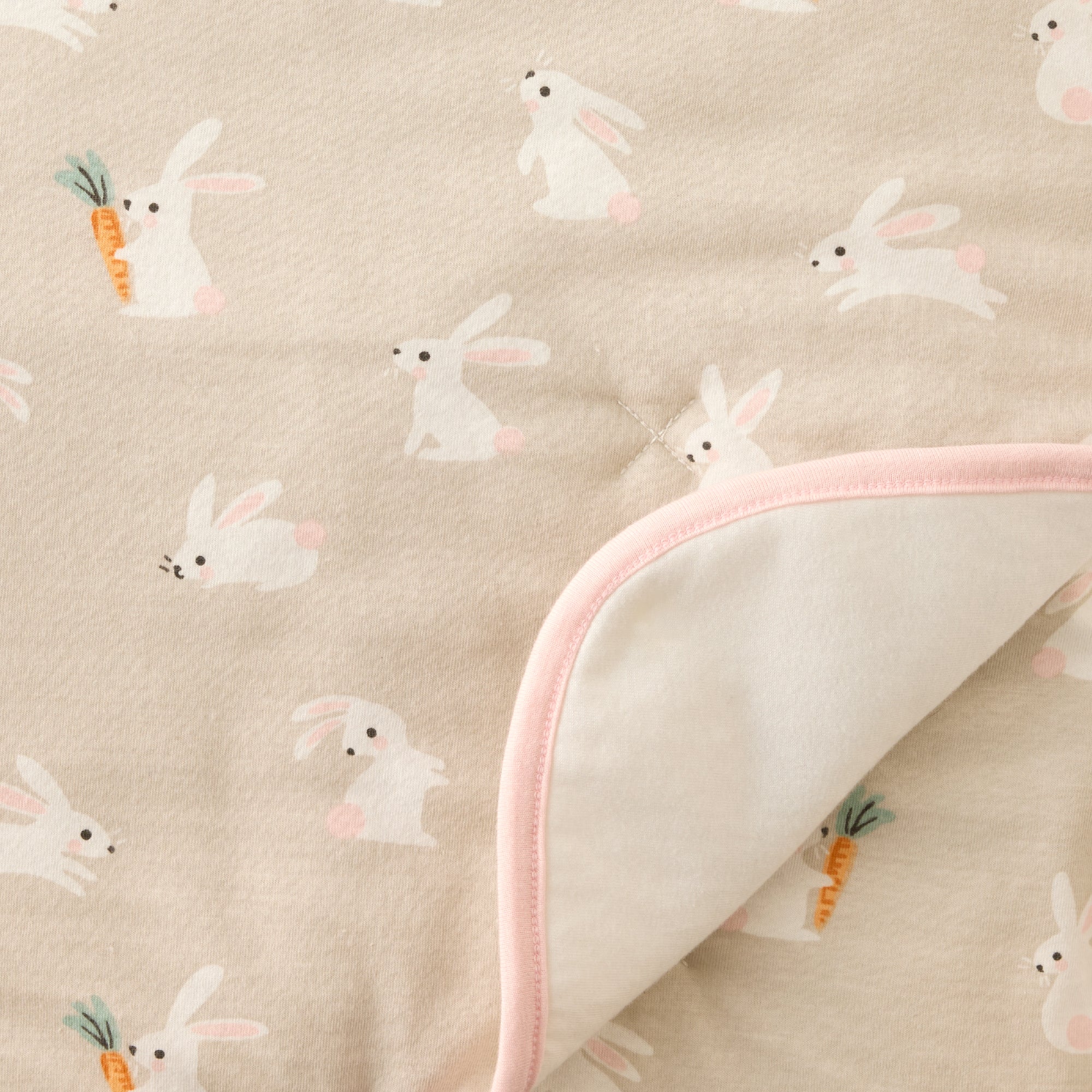 Fabric with bunny pattern and pink trim on a beige background