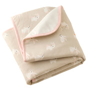 Folded baby blanket with pink border and animal pattern on beige background