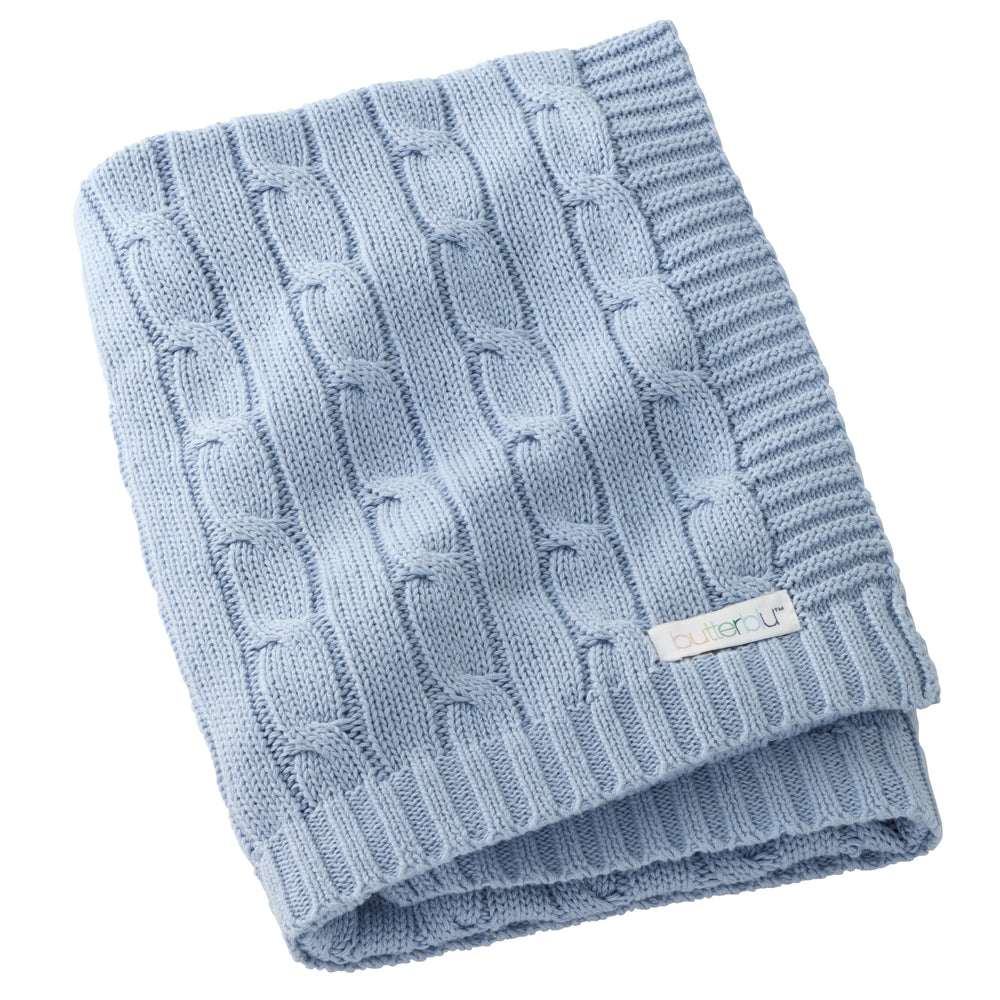 Folded blue knitted blanket with a brand label on a white background