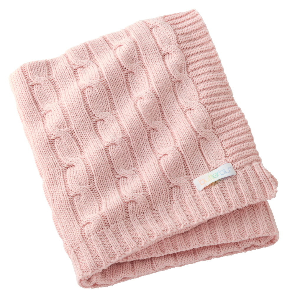 Pink knitted blanket with a visible brand label on a white background
