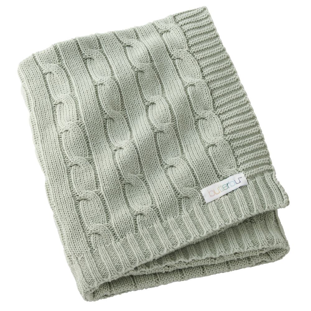 Folded green knitted blanket with a brand label on a white background