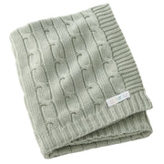 Folded green knitted blanket with a brand label on a white background