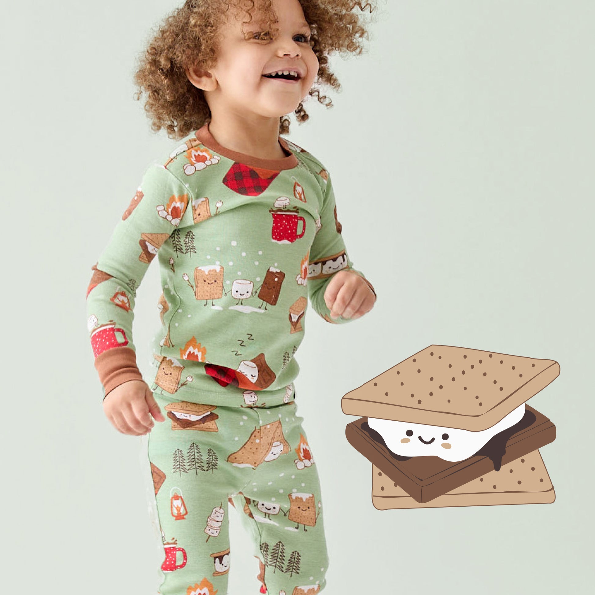 Child wearing a green pajama set with forest animal print, standing next to a cartoon s'mores graphic.