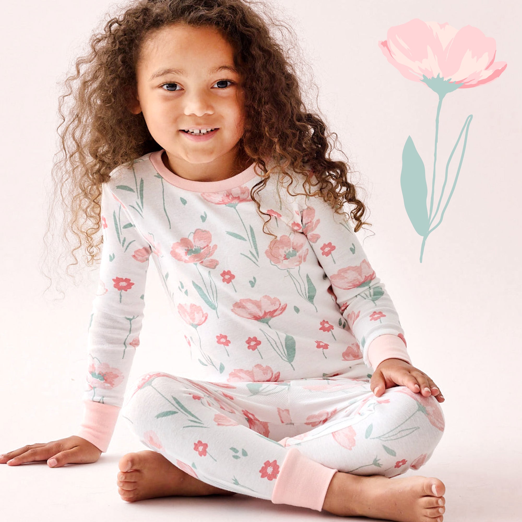 Child wearing a floral pajama set with a pink flower in the background