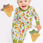 Baby wearing a colorful pajama set with food patterns, surrounded by cartoon tortilla chips on a white background.