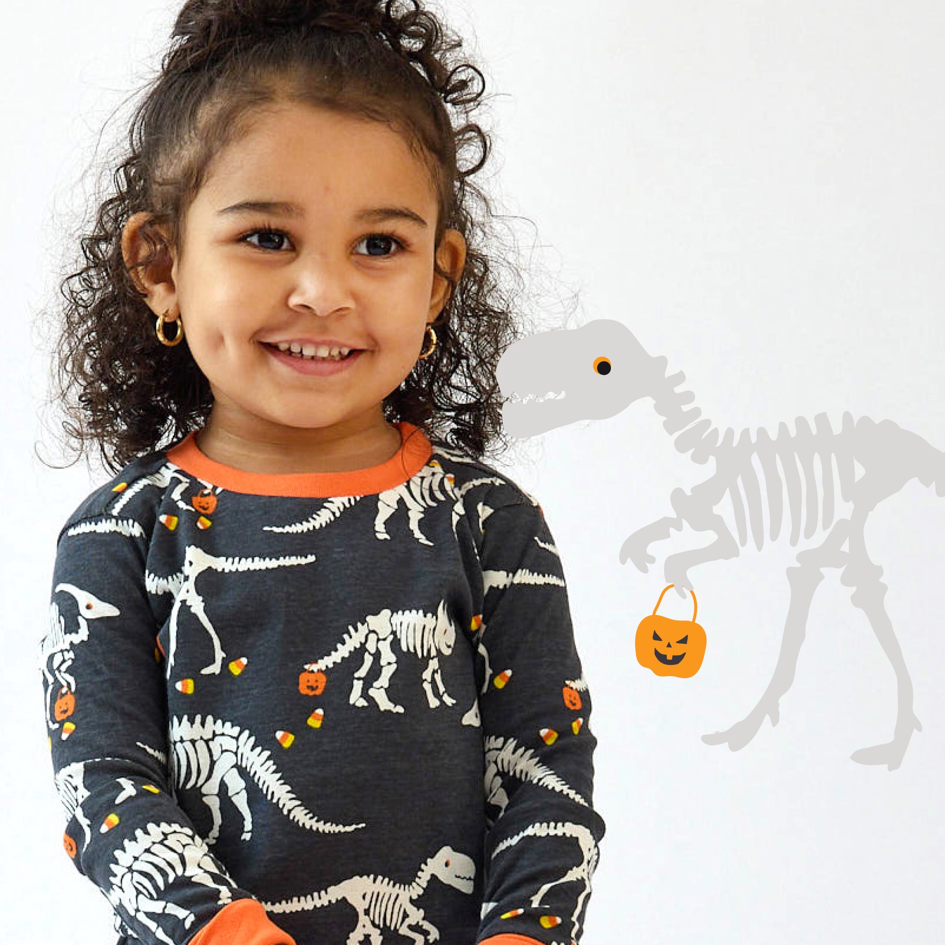 Child wearing a dinosaur-themed shirt with Halloween elements on a white background