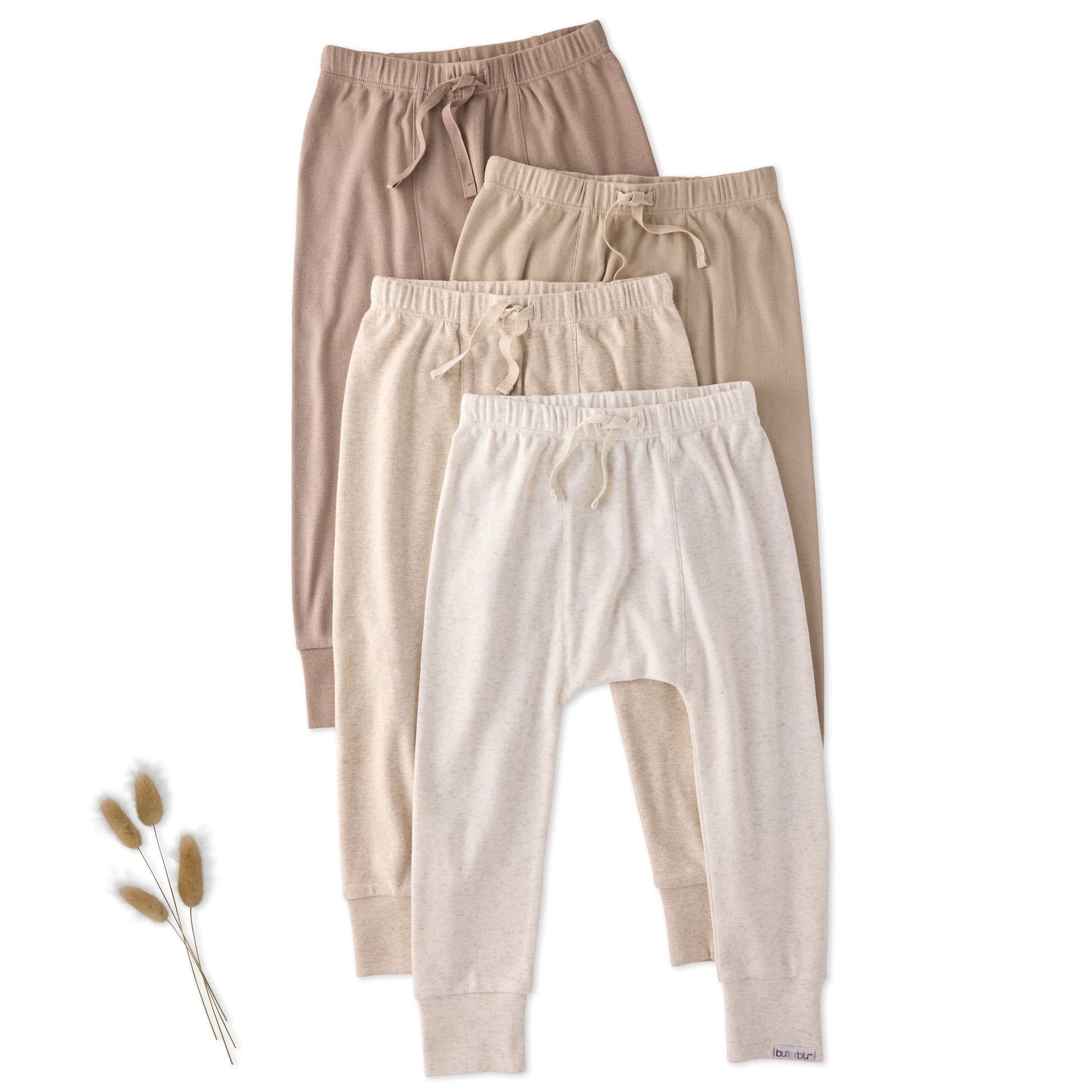 Three pairs of kids pants in beige, brown, and white on a white background.